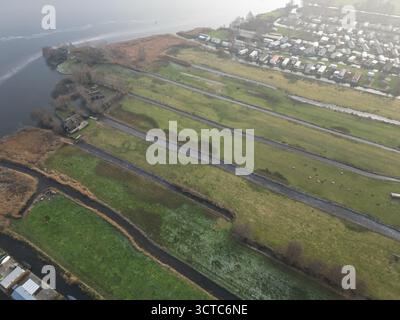 Vista aerea dei tranquilli corsi d'acqua che riflettono il cielo ammutinato, scavando tra i campi verdi e le case pittoresche, Giethoorn, Overijssel, Paesi Bassi. Foto Stock