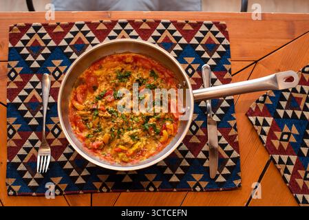 Shakshuka colorato in un tappetino da tavolo con motivo Pan-on Foto Stock