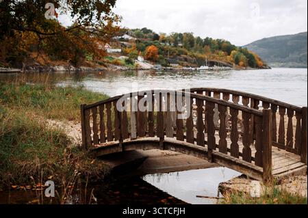 Ponte di legno autunnale su un fiume sereno Foto Stock