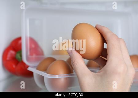 Donna che prende l'uovo di pollo crudo dal frigo, primo piano Foto Stock