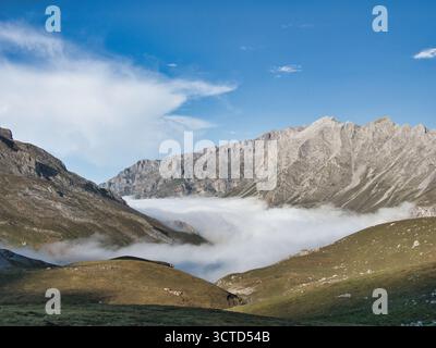 Sentiero sterrato che conduce a maestose vedute montane - ripresa grandangolare di un sentiero roccioso che conduce ad un panorama montano di alta quota con nebbia e bassa Foto Stock