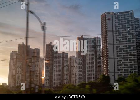 Moderni ed alti edifici di appartamenti a Seoul durante il tramonto, visti da un treno in movimento. Foto Stock