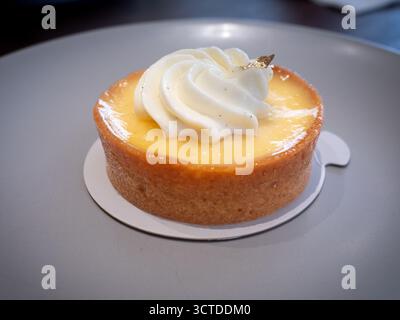 Guscio di crostata farcita di scorza di limone, ricoperto di panna montata alla vaniglia e foglia d'oro, per creare un dessert ricco ma rinfrescante. Foto Stock