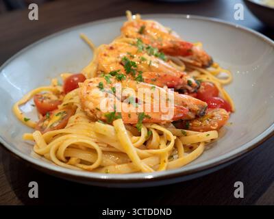 Un piatto di pasta di linguine condito con grandi gamberi succosi in salsa piccante e infuso di aglio. Foto Stock