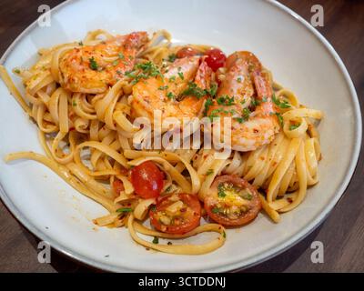 Un piatto di pasta di linguine condito con grandi gamberi succosi in salsa piccante e infuso di aglio. Foto Stock