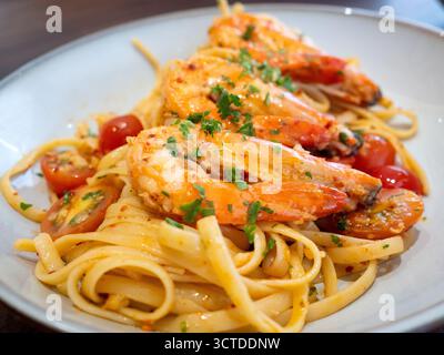 Un piatto di pasta di linguine condito con grandi gamberi succosi in salsa piccante e infuso di aglio. Foto Stock