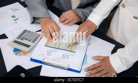 Primo piano di donne d'affari che analizzano il foglio di calcolo finanziario e il grafico dei dati con la calcolatrice sulla scrivania dell'ufficio. Concetto di lavoro di squadra, contabilità, piano finanziario Foto Stock