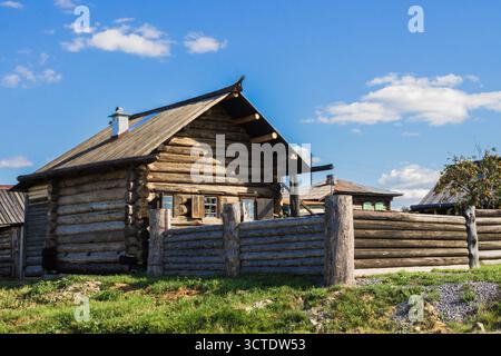 Vecchia casa rustica in legno in un tradizionale villaggio rurale nella regione degli Urali in Russia. Architettura storica in legno e tranquillo paesaggio di campagna Foto Stock
