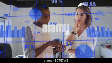 Esaminando un tablet, due donne aziendali analizzano i dati in un ufficio moderno con grafici fluttuanti Foto Stock