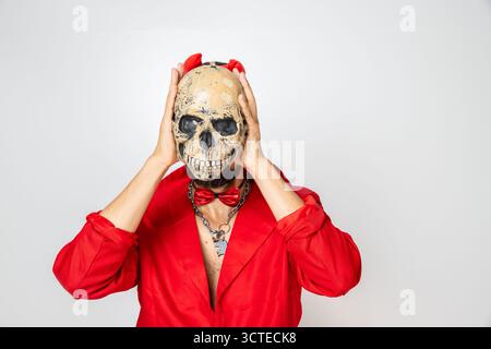 modello vestito con una tuta rossa che tiene un teschio davanti al viso Foto Stock