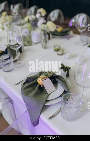 Questa immagine mostra un tavolo splendidamente disposto con un tovagliolo verde e un limone decorativo per un tocco elegante, mettendo in risalto il motivo floreale ce Foto Stock