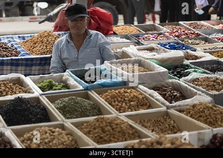 Kashgar, Cina - 07 settembre 2025: Vista di un venditore tra una vivace gamma di frutta secca, noci e dolci, ognuno nel proprio scomparto, creando un mosaico di texture e tonalità terrose. Foto Stock