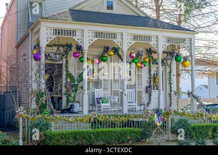 New Orleans, LOUISIANA, Stati Uniti - 31 gennaio 2025: Fronte della storica casa di fucili camelback con decorazioni del Mardi Gras e un cane che riposa sul portico, nel quartiere Uptown Foto Stock