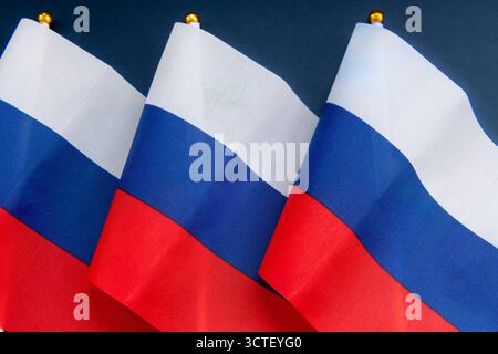 Una fila di bandiera della Federazione Russa su pali di bandiera isolati in blu scuro. Foto Stock