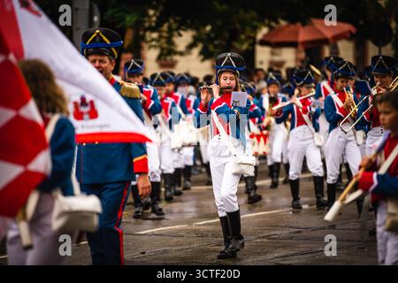 Monaco, Germania - 18 settembre 2022: Vista di una vivace sfilata dell'Oktoberfest con musicisti in uniforme blu e bianca che marciano per le strade della città. Foto Stock