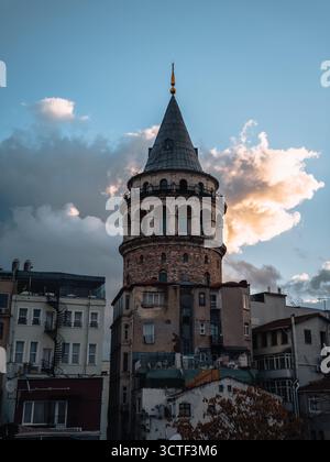 La vista della Torre Galata è alta, un faro della storia contro una tela di nuvole drammatiche e cieli scuri, Istanbul, İstanbul, Türkiye. Foto Stock