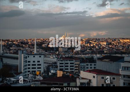 Vista di un vasto paesaggio urbano sotto un cielo drammatico, di edifici sottostanti e di una moschea in lontananza con minareti che perforano lo skyline, Istanbul, İstanbul, Türkiye. Foto Stock