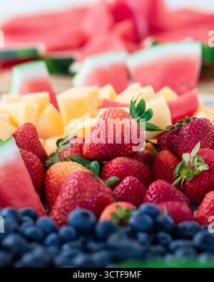 Un vivace assortimento di frutta fresca estiva, tra cui fragole, mirtilli, anguria e cantaloupe, disposti su un piatto. Foto Stock