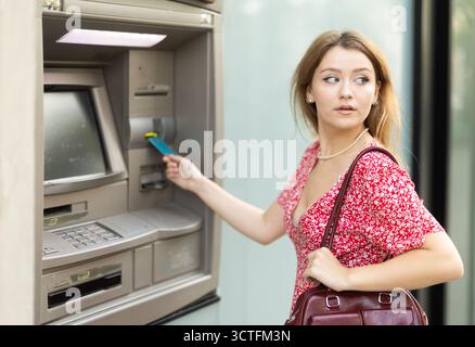Giovane donna che usa la carta al bancomat Foto Stock