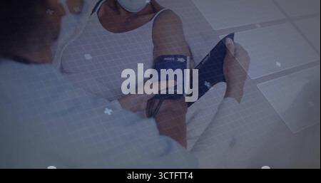 Avvolgimento di un medico mascherato che posiziona il bracciale per la pressione sanguigna sul braccio del paziente nella sala esame con pannelli UI Foto Stock