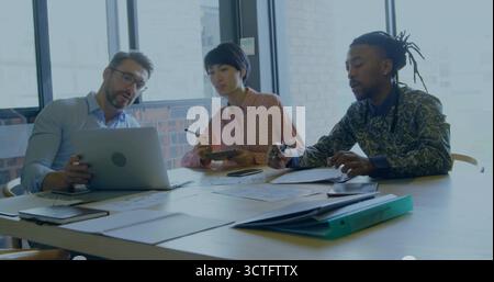 Tre professionisti che analizzano i referti in una sala riunioni con raccoglitore per calcolatrici per computer portatili Foto Stock