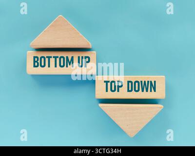 Concetto bottom-up e top-down su blocchi di legno con frecce che rappresentano strategie e metodologie aziendali conflittuali Foto Stock