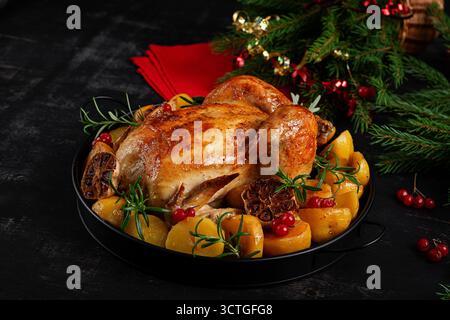 Pollo arrosto con patate e decorazioni natalizie. Impostazione della tavola. Pollo o tacchino al forno. Primo piano Foto Stock