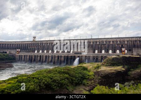 Itaipu Binacional, Brasile - 22 giugno 2025: La base della struttura della diga, evidenziando la scala della centrale elettrica e del canale idrico adiacente. Foto Stock