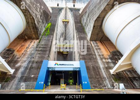 Itaipu Binacional, Brasile - 22 giugno 2025: Riprese ad angolo basso che sottolineano l'altezza torreggiante e la complessità strutturale della diga binazionale di Itaipu. Foto Stock