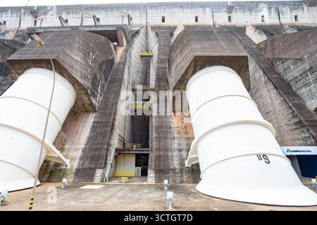 Itaipu Binacional, Brasile - 22 giugno 2025: Vista ravvicinata dei tubi di pescaggio delle turbine bianche giganti che emergono dalla massiccia faccia in cemento dell'Itaipu D. Foto Stock