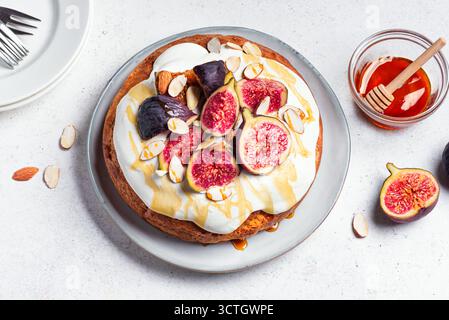 Torta in spugna al miele con panna montata, fichi e mandorle, vista dall'alto. Torta autunnale di stagione fatta in casa con frutta e noci. Foto Stock