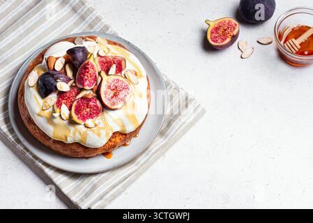 Pan di Spagna al miele con panna montata, fichi e mandorle, vista dall'alto, spazio per copiare. Torta autunnale di stagione fatta in casa con frutta e noci. Foto Stock