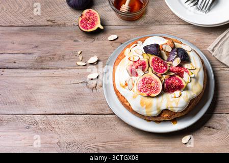 Pan di Spagna al miele con fichi, formaggio cremoso montato su sfondo di legno, spazio copia. Ricetta per dolci di stagione per le vacanze autunnali. Foto Stock