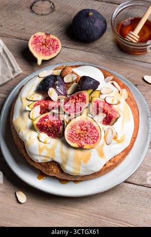 Pan di Spagna al miele con fichi, mandorle e formaggio cremoso montato su un tavolo di legno. Ricetta per dolci di stagione per le vacanze autunnali. Foto Stock