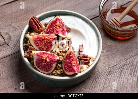 Ciotola con fichi e noci pecan. Ciotola per la colazione con yogurt greco, muesli, miele, frutta e noci. Pasto sano equilibrato. Foto Stock