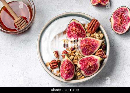 Ciotola con fichi e noci pecan da vicino. Cestino per la colazione con yogurt, muesli, miele, frutta e noci. Foto Stock