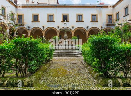 Il giardino del chiostro del Santuario Santa Rita da Cascia, chiamato anche Chiesa di Sant'Agostino, Palermo, Sicilia, Italia. Giardino verde centrale con statua Foto Stock