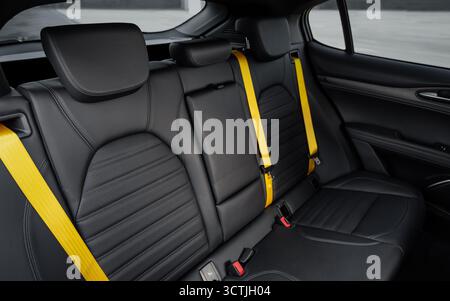 Sedili posteriori in pelle con cinture di sicurezza gialle in una vettura. Interni Hatchback o SUV in pelle nera e rivestimento padiglione. Foto Stock