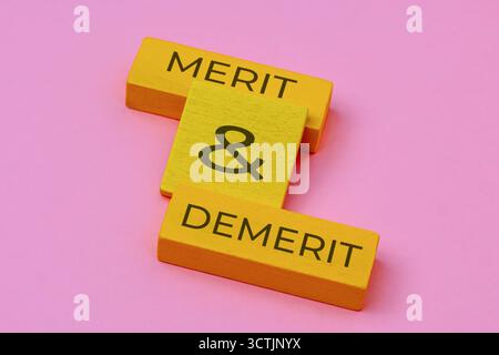 Blocchi di legno che mostrano MERITI e DEMERITI. Un'immagine concettuale per valutare pro e contro, vantaggi, svantaggi e decisioni aziendali. Foto Stock