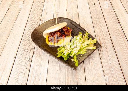Panino Bao con pollo teriyaki e insalata di lattuga su tavola bianca Foto Stock