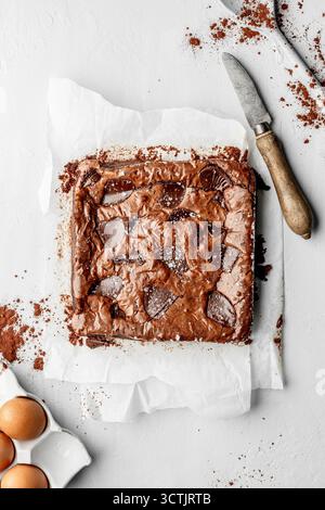 Lastra di brownie al cioccolato appena sfornata su carta pergamena, fotografata con luce naturale soffusa per prodotti da forno e dessert. Foto Stock