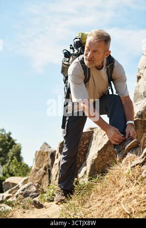 Un uomo anziano attivo ama trascorrere una bella giornata facendo escursioni in montagna, circondati da paesaggi mozzafiato. Foto Stock