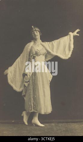Un prigioniero di guerra in trascinamento, con indosso un vestito e un mantello bianco, posa a metà movimento con le braccia allungate (tra il 1910 e il 1919?). Foto Stock