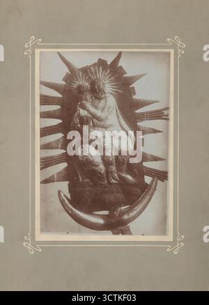 Nostra Signora con bambino, (1900-1914). Madonna con bambino, un "rilievo" in metallo (ribollito, risucchio&#xe9;, cesellato e dorato). È probabilmente il finale di una chiesa del XVIII secolo. La Vergine Maria che tiene il bambino è raffigurata in una posa seduta in trono, sostenuta da nuvole. Al di sotto si trova una mezzaluna di lamiera forgiata su un nucleo di legno, simbolo dell'Immacolata Concezione. Fotografo sconosciuto. Foto Stock