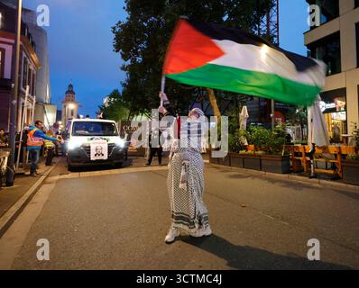Pro-Palästina-Demo 07.10..2025 am Abend findet am zweiten Jahrestag des Hamas-Überfalls auf Israel ein Pro-Palästina-Demonstrationszug in schwarzer Kleidung mit roten Rosen mit dem Titel 77 Jahre Widerstand kein Frieden ohne Freiheit ab der Hauptwache statt. Diesen hatte das Frankfurter Ordnungsamt verboten, aber das Frankfurter Verwaltungsgericht aufgehoben hier einzelne Fahnenträgerin Frankfurt Main Hessen Deutschland *** manifestazione pro Palestina 07 10 2025 la sera, in occasione del secondo anniversario dell'attacco di Hamas contro Israele, una manifestazione pro Palestina in abiti neri con ros rossi Foto Stock