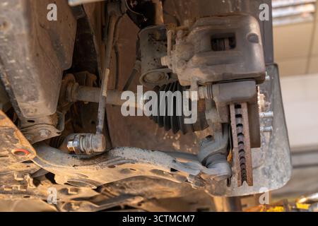 Primo piano del mozzo della ruota anteriore di un'auto con meccanismo del freno, bracci delle sospensioni, albero di trasmissione e giunto omocinetico in un soffietto in gomma. Concetto di riparazione auto. Foto Stock