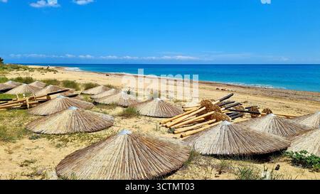 Paesaggio panoramico con mare turchese e ombrelloni di paglia sdraiati su una spiaggia sabbiosa a Cefalonia, Grecia Foto Stock