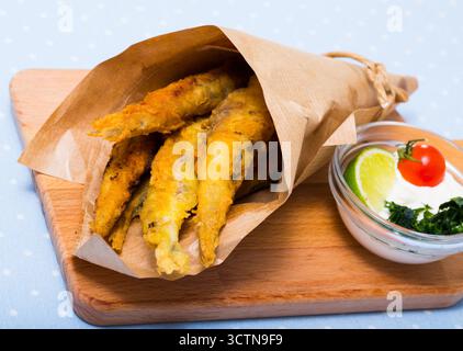 Acciughe fritte in padella con salsa cremosa al formaggio, verdure Foto Stock