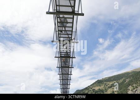 La vista ad angolo basso dei visitatori che camminano sul Ponte tibetano, un ponte sospeso in metallo di 603 m oltre 158 m di profondità nella valle di Vall del Riu, Canillo, Andorra Foto Stock