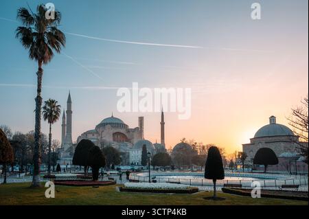 L'alba dorata illumina un grande parco di Istanbul con la Basilica di Santa Sofia che si innalza maestosamente sullo sfondo, evidenziando le sue iconiche cupole Foto Stock
